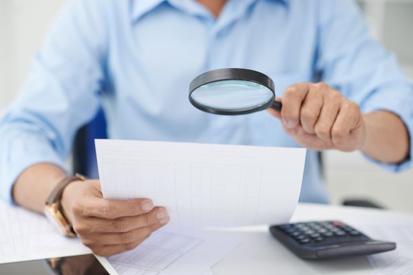 hombre mirando un documento con lupa